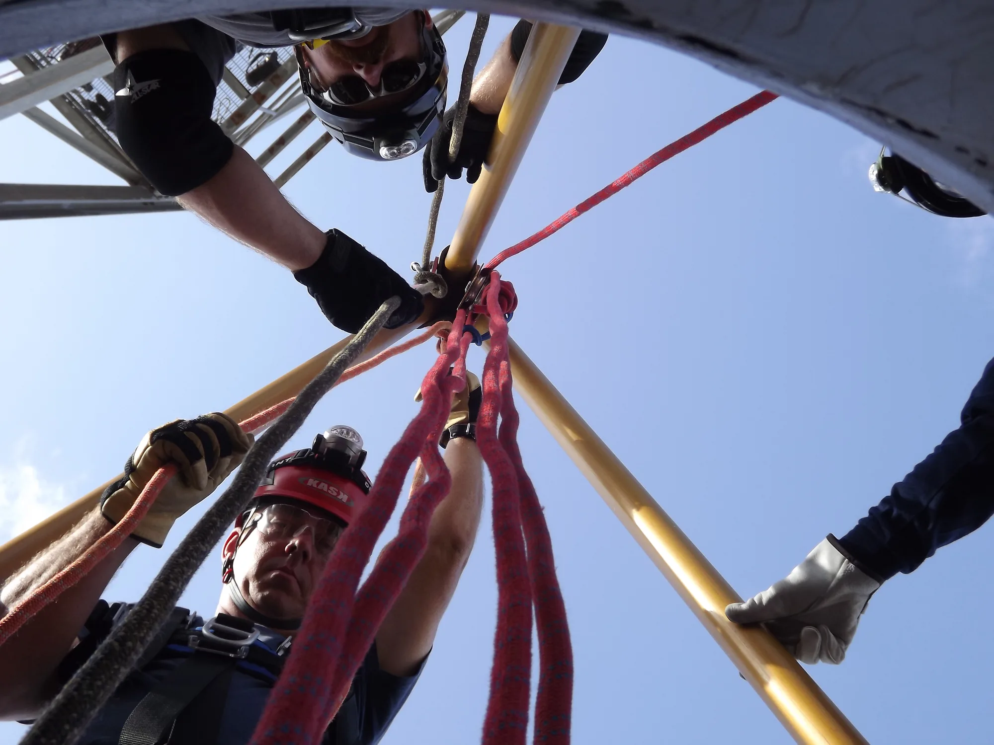 Rope rescue team working on tripod rigging viewed from below